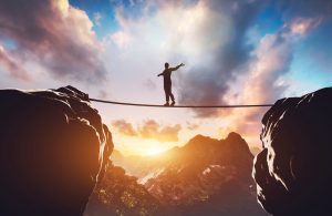 an image of a man walking a tight rope between two mountains